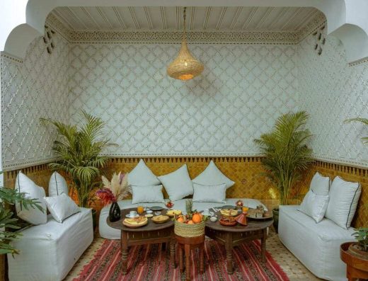Salon extérieur blanc avec plantes vertes et tapis marocain riad Dahino