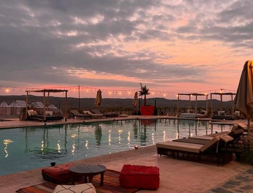 Piscine sous un coucher de soleil dan sle désert d'Agafay